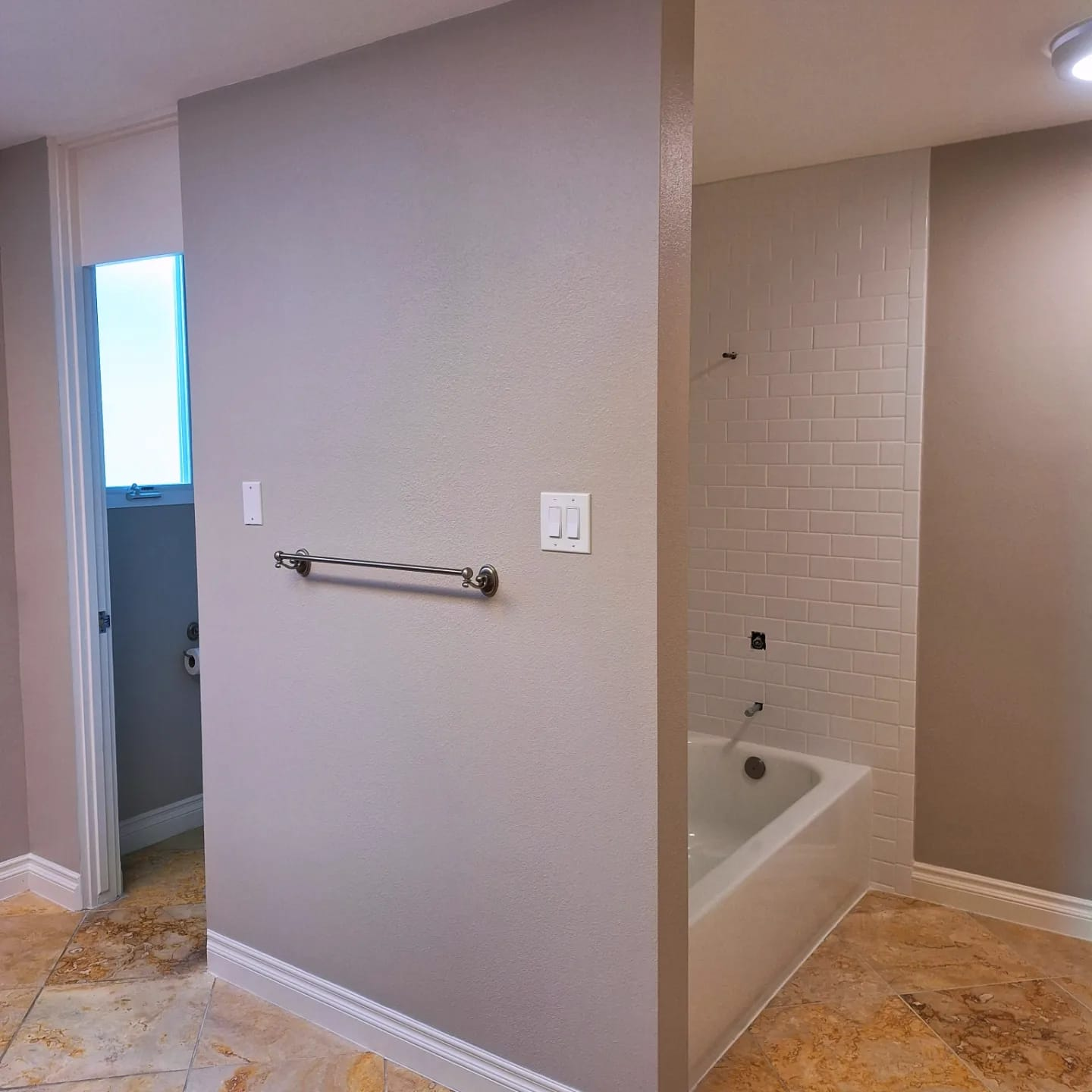 Finished painted bathroom wall with tiled tub area