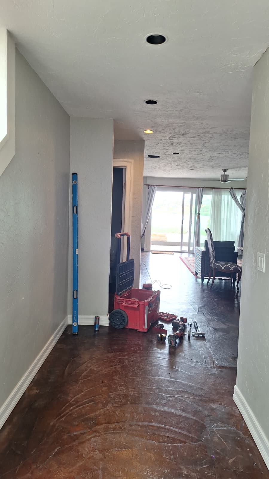 Interior hallway opening toward the living area with tools on the floor