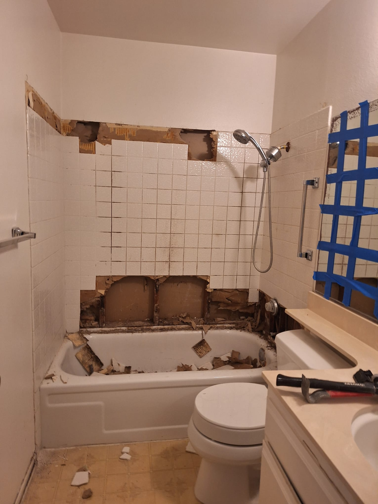Bathroom with tub surround tile and drywall partially removed