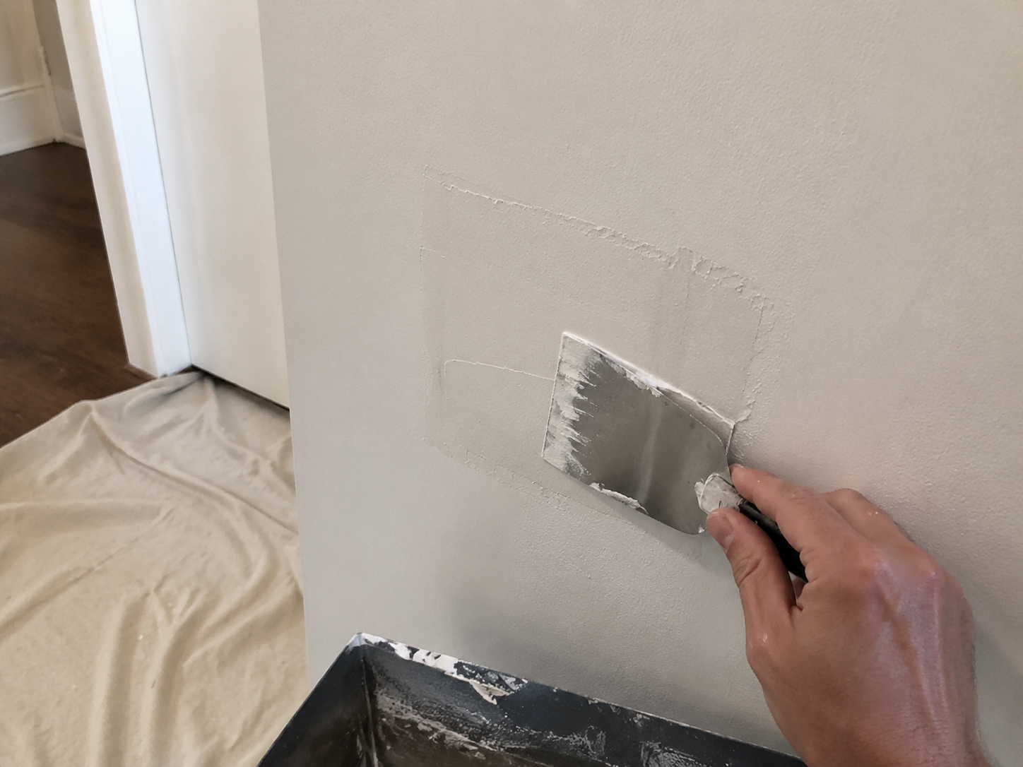 Putty knife applying compound to patch drywall