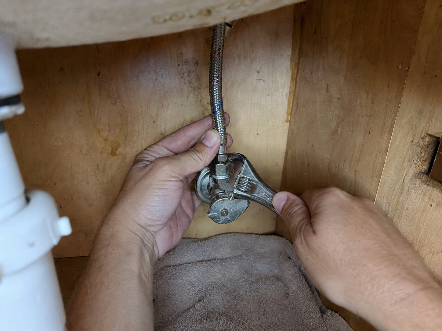 Wrench tightening plumbing connections under a sink